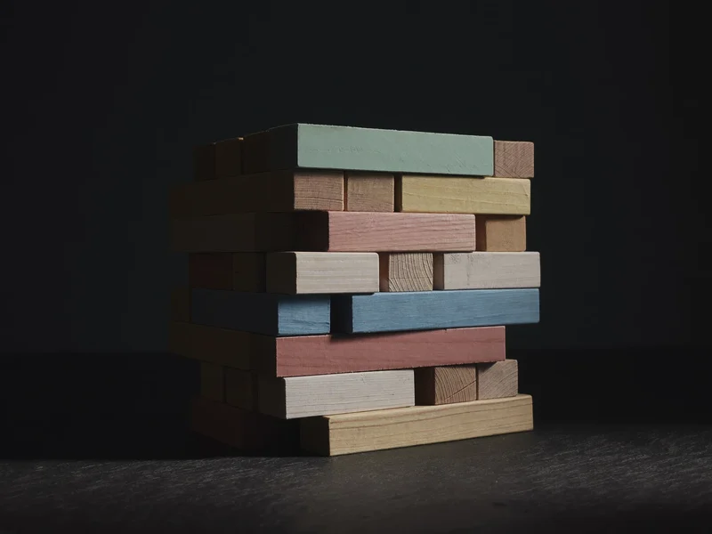 Blocs de construction en bois naturel aux tons pastel sur une ardoise sombre