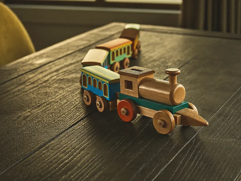 Train en bois à tirer aux wagons peints sur une table en chêne foncé