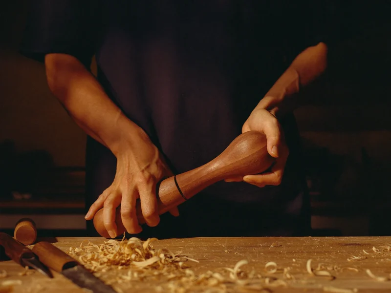 Mains d'artisan poncant une pièce de jouet en bois dans un atelier chaleureux