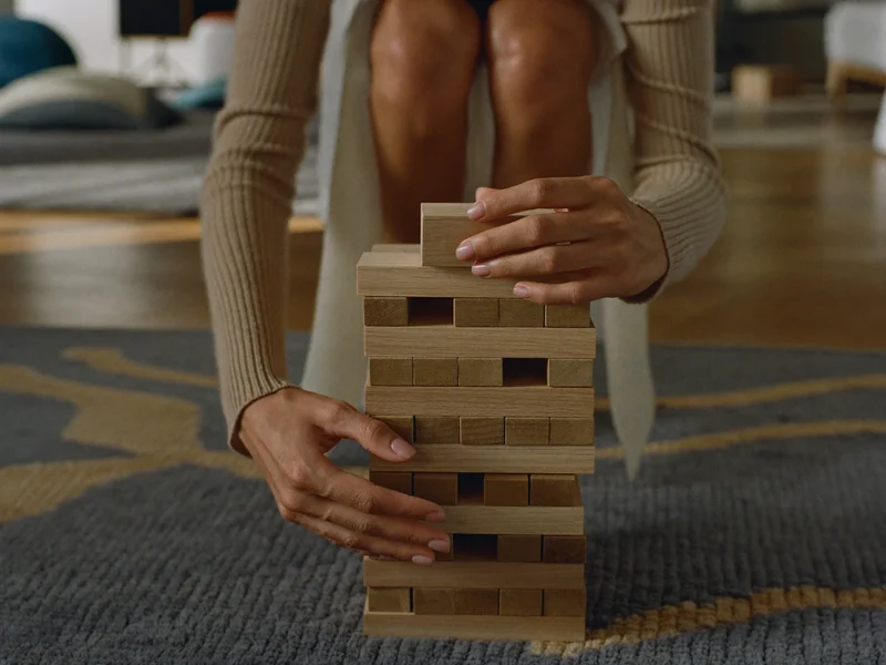 Mains d'enfant posant un bloc sur une tour, sur un tapis dans une chambre de jeu